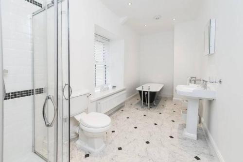 Baño blanco con aseo y lavamanos en Coach House, Middleton Hall Estate en Belford