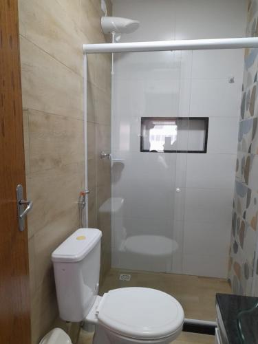 a bathroom with a toilet and a glass shower at Suíte Itaipu Mar in Vila Velha