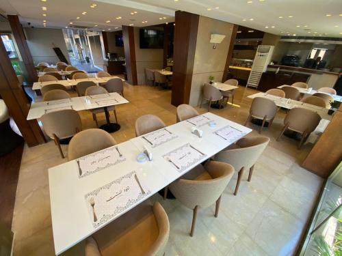 a dining room with white tables and chairs at Lancaster Suites Raouche in Beirut