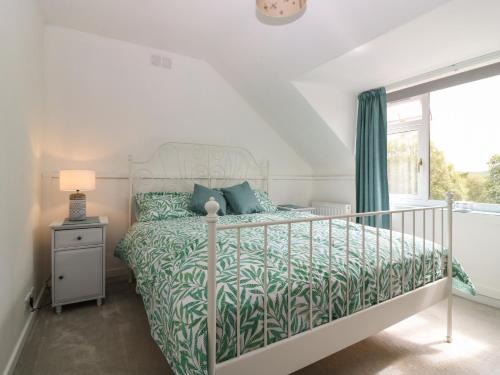 a bedroom with a bed with a green bedspread and a window at 2 Station Road East in Peterculter