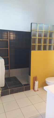 een badkamer met een toilet en een gele en zwarte muur bij Gîtes Monoï 4 personnes refait en 2023 avec piscine privée in Saint-François