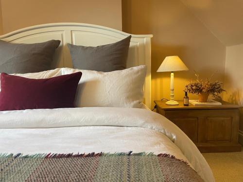 um quarto com uma cama grande com almofadas e um candeeiro em Idyllic cosy cottage close to Oxford and Le Manoir em Cuddesdon