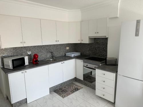 a kitchen with white cabinets and a white refrigerator at Castle Harbour Home in Los Cristianos
