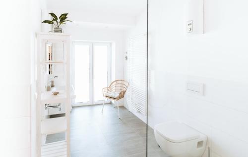 a white bathroom with a toilet and a chair at Deichstadt Apartments in Neuwied