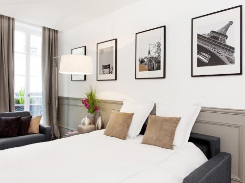 - une chambre avec un grand lit blanc et des photos encadrées de la tour Eiffel dans l'établissement LivinParis - Luxury 3 Bedrooms Grands-Boulevards I, à Paris