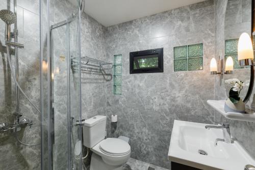 a bathroom with a toilet and a shower and a sink at Le Charcoa Hotel in Chiang Mai