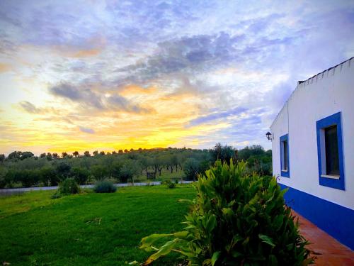 a house with a green field and a sunset at Casa de Campo, Quinta do Funchal in Arraiolos