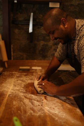 a man is kneading a dough on a table at Vanilla County in Vagamon