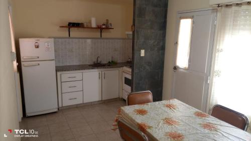 a kitchen with a table and a white refrigerator at Mi Casita in Bahía Blanca