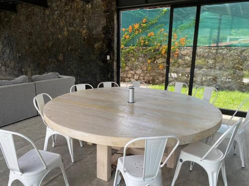 mesa de madera con sillas blancas y ventana grande en Casa Aurora (completamente nueva) en Tepoztlán