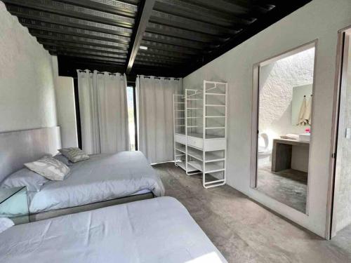 1 dormitorio con 2 camas y espejo en Casa Aurora (completamente nueva) en Tepoztlán