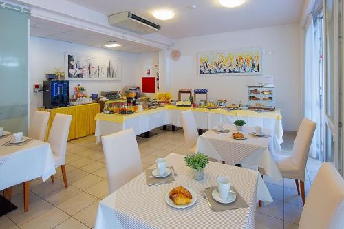 Un comedor con mesas blancas y sillas blancas. en Hotel Ginevra, en Lido di Jesolo