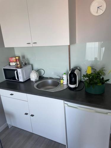 a kitchen with a sink and a microwave at Apartament KORNER Chełmońskiego Śrem in Śrem