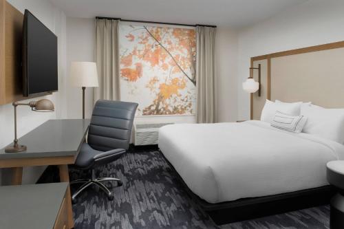 a hotel room with a white bed and a desk and a window at Fairfield Inn & Suites Nashville Near Vanderbilt in Nashville