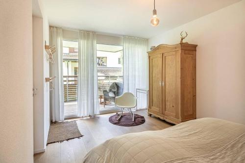 a bedroom with a bed and a chair and a window at 10min zu den Bergbahnen Tiefgarage & Wifi inkl. Bergsicht & Ruhe 
