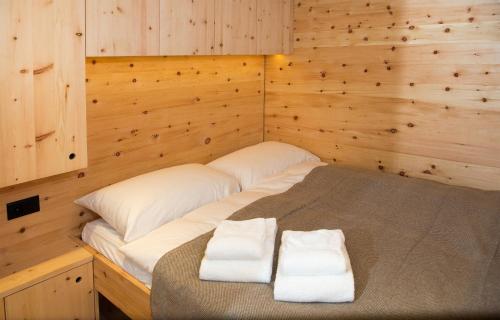 a bed in a wooden room with two towels at Mountain Cabin Got Spess Lenzerheide in Obervaz