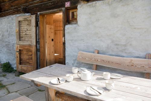 une table en bois avec des assiettes, des tasses et un banc dans l'établissement Mountain Cabin Got Spess Lenzerheide, à Obervaz