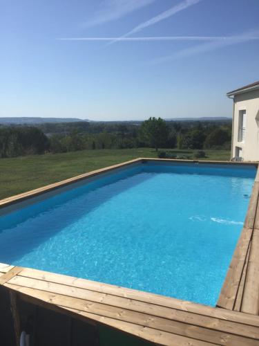 une grande piscine bleue avec une terrasse en bois dans l'établissement Maison Origami, à Villeneuve-sur-Lot
