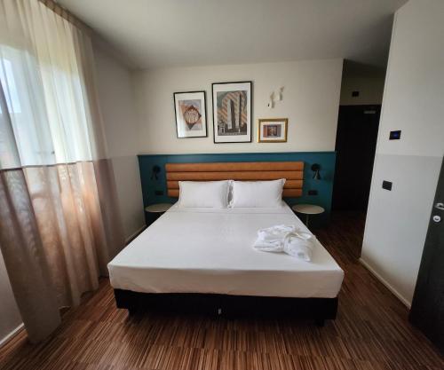 een slaapkamer met een groot bed met witte lakens bij Hotel Imperial in Bologna