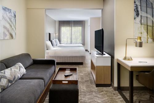 uma sala de estar com um sofá e uma cama num quarto de hotel em SpringHill Suites Raleigh-Durham Airport/Research Triangle Park em Durham