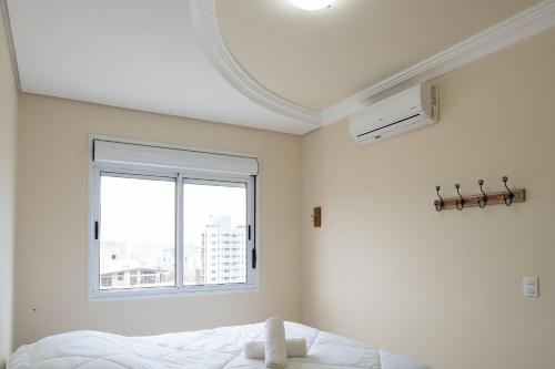 a white bedroom with a bed and a window at Apto elegante para casal em POA-RS URB1110 in Porto Alegre