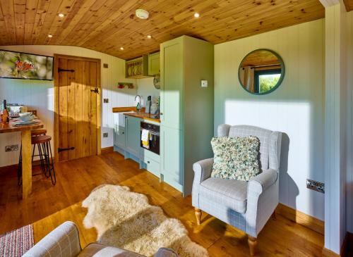 a living room with a chair and a kitchen at Abberley Shepherds Hut - Ockeridge Rural Retreats in Wichenford