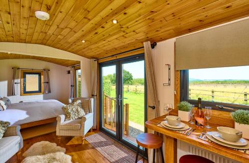 a bedroom with a bed and a view of a field at Abberley Shepherds Hut - Ockeridge Rural Retreats in Wichenford