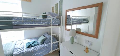 1 dormitorio con 2 literas y espejo en Cheerful 2 bed home with mountain views en Blaenau-Ffestiniog