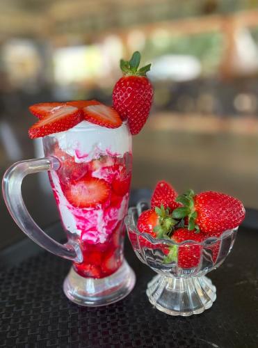 een glazen kan gevuld met aardbeien en een kom aardbeien bij D-LITE COTTAGE in Mahabaleshwar