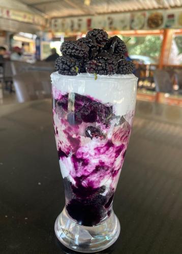 een dessert met bramen en slagroom in een glas bij D-LITE COTTAGE in Mahabaleshwar