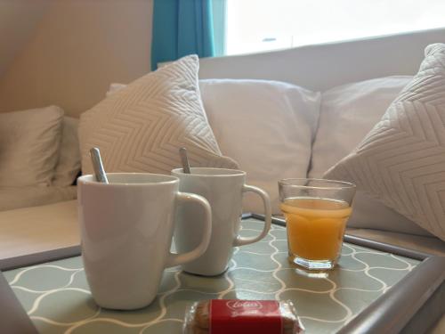 a table with two cups and a glass of orange juice at The Carpenters Arms Rooms in Broadway, Laugharne in Laugharne