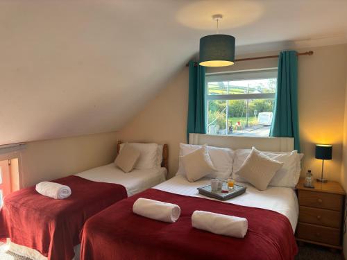 a bedroom with two beds with red sheets and a window at The Carpenters Arms Rooms in Broadway, Laugharne in Laugharne