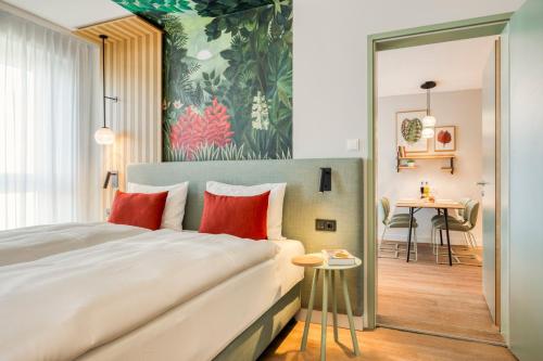 a hotel room with a large bed with red pillows at Citadines Danube Vienna in Vienna