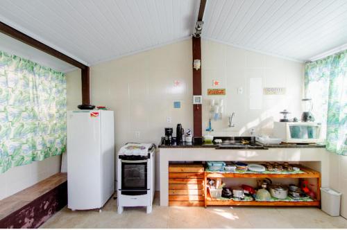 a kitchen with a white refrigerator and a stove at Pousada Canto do Mar Ilha Grande in Praia de Araçatiba