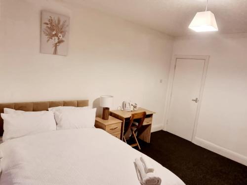 a bedroom with a white bed and a desk with a lamp at Lilies Lodge in Balby