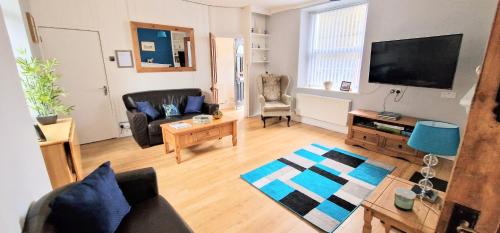 a living room with a couch and a tv at Cheerful Snowdonia cottage,garden snug, mountain views, sleeps 4, near zip world in Blaenau-Ffestiniog