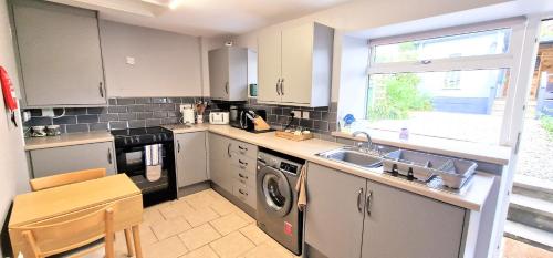 a kitchen with a sink and a washing machine at Cheerful Snowdonia cottage,garden snug, mountain views, sleeps 4, near zip world in Blaenau-Ffestiniog