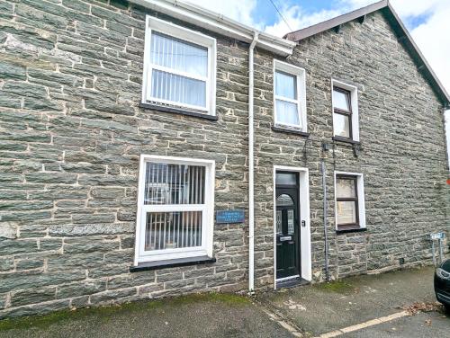 a brick house with white windows and a door at Cheerful Snowdonia cottage,garden snug, mountain views, sleeps 4, near zip world in Blaenau-Ffestiniog