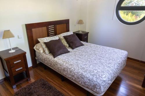 een slaapkamer met een bed, 2 tafels en een raam bij Piso nuevo cerca de Santander in Soto de la Marina
