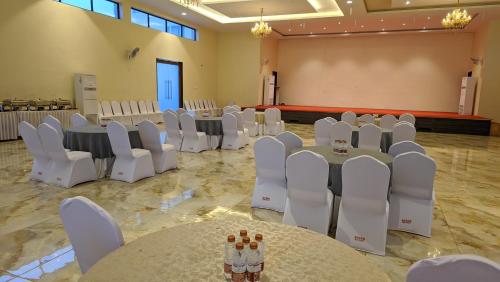 a banquet hall with white tables and white chairs at Mayur Belgaum Presidency Hotel & Spa in Belgaum