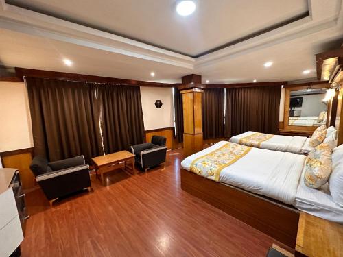 a hotel room with a large bed and two chairs at Hotel Gajraj in Gangtok