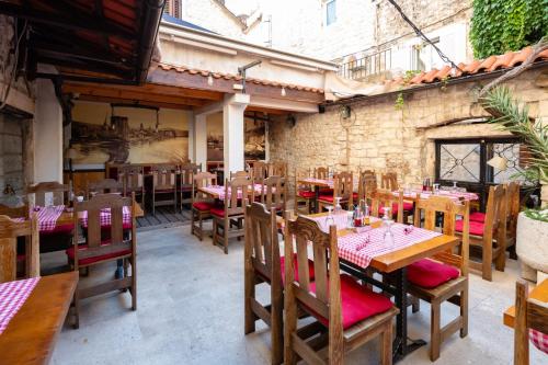 a restaurant with wooden tables and chairs and a brick wall at Heritage Hotel Tragos in Trogir