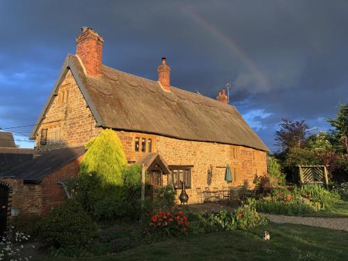 an old brick house with a thatched roof at Hunt House Rooms in Kilsby
