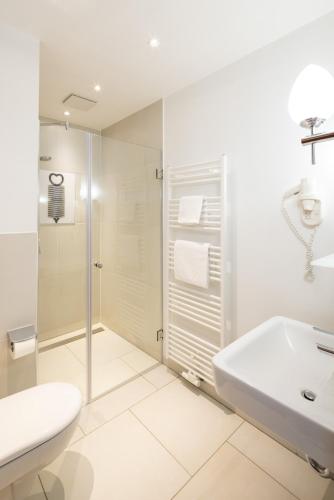 a white bathroom with a shower and a sink at Schloss Hertefeld & Hertefeldhof in Weeze