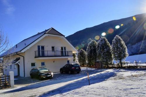 a house with two cars parked in the snow at quiet and central Luxury Villa "JUWEL" with Sauna, at Ski slope! in Sankt Michael im Lungau