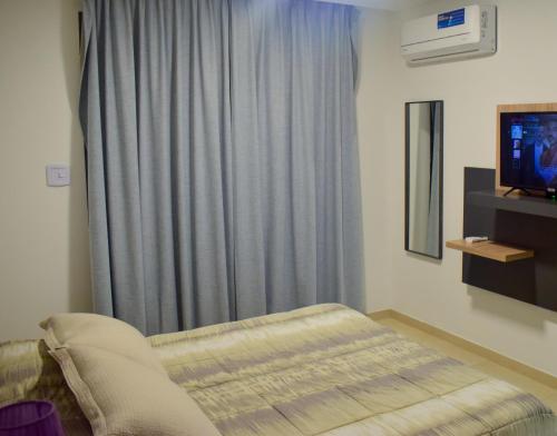 a bedroom with a bed and a window with a television at Agustín I Apart in Paraná
