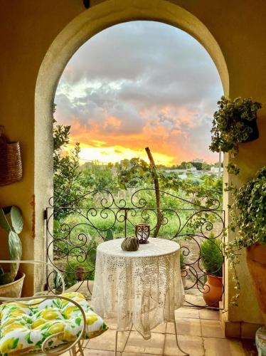 a table on a balcony with a view of a sunset at La finestra sul limone in Castelvetrano Selinunte