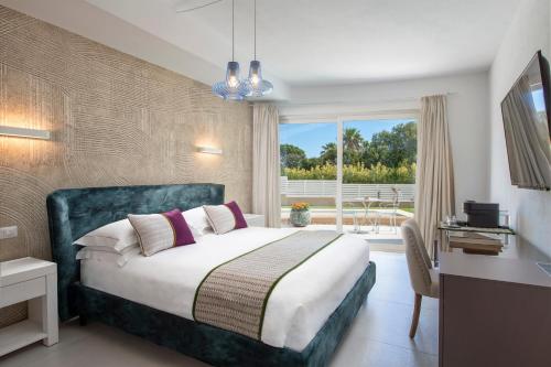 Schlafzimmer mit einem Bett, einem Schreibtisch und einem Fenster in der Unterkunft Villa Escargot Luxury in Costa Rei Beach in Costa Rei
