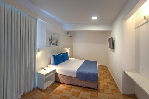 a hotel room with a bed with blue pillows at Express Floripa Residence in Florianópolis