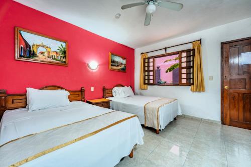 a bedroom with two beds and a red wall at Hotel Santa Lucía in Mérida